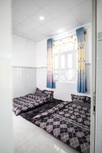 Ngôi nhà nhỏ Lagi Homestay في لاغي: سريرين في غرفة مع ستائر زرقاء