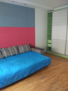a bedroom with a blue bed and a pink wall at Апартаменти Volodymyra Velykoho in Ivano-Frankivsʼk