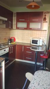 a kitchen with brown cabinets and a table with a microwave at Апартаменти Volodymyra Velykoho in Ivano-Frankivsʼk
