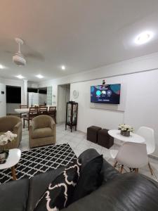 a living room with a couch and a tv on the wall at Praia do Tombo in Guarujá