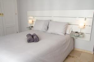 Una cama blanca con dos toallas encima. en Villa Infante, en Huelva