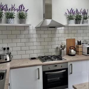 a kitchen with a stove and some purple plants at Stylish Boatwright Cottage moments from beach by Whitstable-Holidays in Whitstable