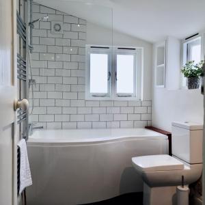 La salle de bains blanche est pourvue d'une baignoire et de toilettes. dans l'établissement Stylish Boatwright Cottage moments from beach by Whitstable-Holidays, à Whitstable