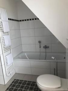 ein weißes Bad mit einem WC und einer Badewanne in der Unterkunft Hus Tina Rügen in Trent