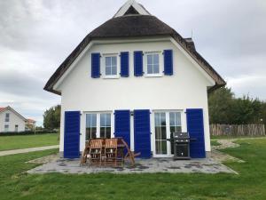 uma casa azul e branca com cadeiras e um grelhador em Hus Tina Rügen em Trent