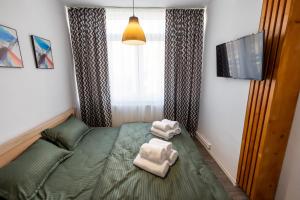 - une petite chambre avec un lit vert et 2 serviettes dans l'établissement New Home Studio, à Zalău