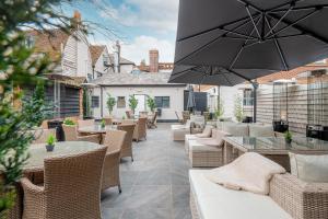 un patio al aire libre con mesas, sillas y una sombrilla en Funky Monk Hotel, en Epping