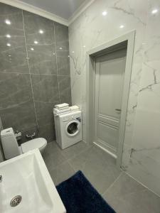 a bathroom with a toilet and a washing machine at 2-х комнатные апартаменты in Taldykolʼ