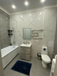 a bathroom with a tub and a toilet and a sink at 2-х комнатные апартаменты in Taldykolʼ