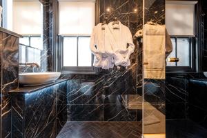 Baño negro con lavabo y espejo en Funky Monk Hotel, en Epping