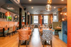 uma sala de jantar com mesas e cadeiras de madeira em Funky Monk Hotel em Epping