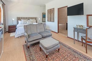 a bedroom with a bed and a couch and a chair at Villa Venusta Luxury Guesthouse - Solar Power in Hermanus