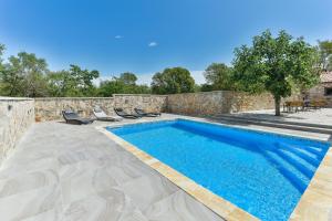a swimming pool with lounge chairs next to a stone wall at NEW! Authentic Stone House Stela & Lea in Zadar