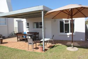 a patio with an umbrella and chairs and a table at Kusweg Suid 4 in Struisbaai