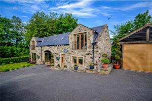 a large stone house with a garage at Bradley Manor, Cosy Retreat For Families & Friends in Huddersfield