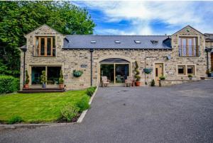 a stone house with a patio and a driveway at Bradley Manor, Cosy Retreat For Families & Friends in Huddersfield