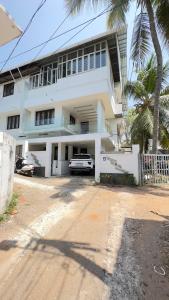 un edificio blanco con un coche aparcado delante de él en Lotus-Explore Kerala 365 en Thiruvananthapuram