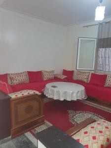 a living room with a red couch and a table at elkbira in Salé