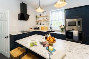 a kitchen with blue cabinets and a bowl of fruit on a counter at Loft Fawr in Tregaron