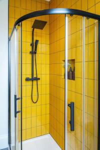 a bathroom with a shower with a yellow tiled wall at Loft Fawr in Tregaron