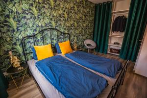 Schlafzimmer mit einem Bett mit blauer Bettwäsche und gelben Kissen in der Unterkunft Stylish Oasis Central Apartment with AC and Parking in Budapest