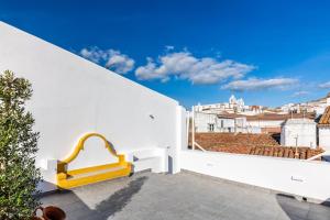 a yellow bench on the balcony of a white building at Evora Spot Rooms in Évora
