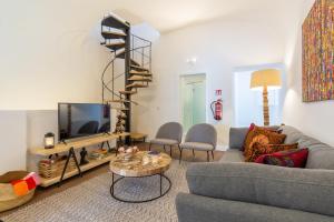 een woonkamer met een bank en een tv bij Evora Spot Rooms in Évora
