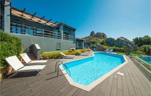 a swimming pool with lounge chairs next to a house at Stunning Home In Trinitadagultu Ot With 6 Bedrooms, Wifi And Outdoor Swimming Pool in Costa Paradiso