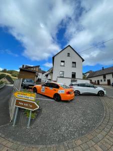 two cars parked in a parking lot in front of a house at Feriënhaus Hohe Acht in Siebenbach