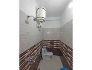 Hotel Tapovan Ganga view, Uttarkashi في Uttarkāshi: حمام به مرحاض وضوء على الحائط