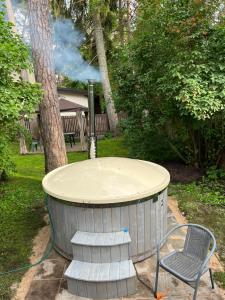 a hot tub in a yard with a chair and a hose at Amber Cottage in Jūrmala