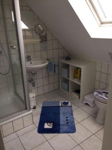 y baño con lavabo, ducha y alfombra azul. en Ferienwohnung "Kleine Krabbe", en Werdum
