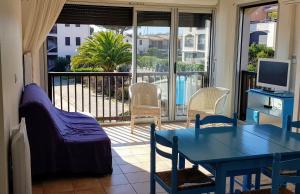 um quarto com uma mesa e cadeiras e uma varanda em Appartement-Marina climatisé 4 couchages avec Piscine em Saint-Cyprien-Plage