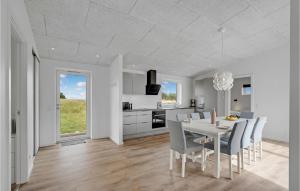 4 Bedroom Gorgeous Home In Lgstrup في Løgstrup: مطبخ أبيض وغرفة طعام مع طاولة وكراسي