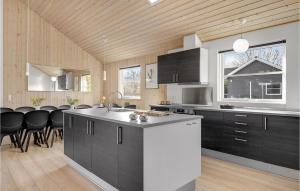 una cucina con armadi neri e piano di lavoro bianco di Amazing Home In Tisvildeleje With Kitchen a Holløselund