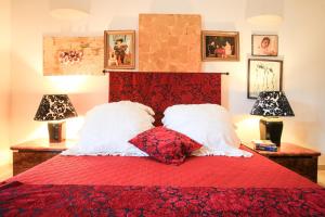 1 cama roja con 2 almohadas y 2 lámparas en Villa con parco e piscina en San Michele Salentino