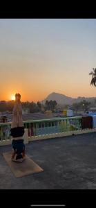 a woman sitting on a mat in front of the sunset at TEMPLE VIEW GUEST HOUSE in Hampi