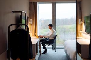 un hombre sentado en un escritorio en una habitación de hotel en Hyatt Place Zurich Airport the Circle, en Kloten