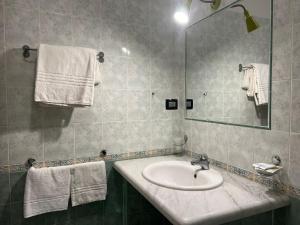 ein Badezimmer mit einem Waschbecken, einem Spiegel und Handtüchern in der Unterkunft Hotel Futuro in Aversa
