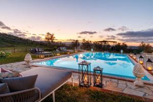 a large swimming pool with a sunset in the background at VILLA LAJATICO Farmhouse with Private Pool in Peccioli