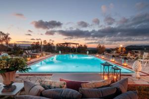 a large swimming pool with couches and a sunset at VILLA LAJATICO Farmhouse with Private Pool in Peccioli