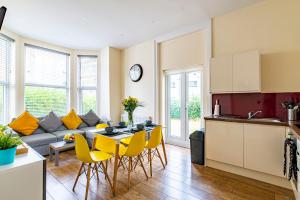 a kitchen and living room with a table and yellow chairs at Greyfriars in Clacton-on-Sea