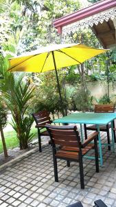 a table and chairs with a yellow umbrella on a patio at Angelica Villa in Bentota