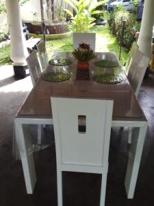 a wooden table with a white chair and a table with plates on it at Angelica Villa in Bentota