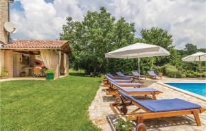 a group of lounge chairs with umbrellas next to a swimming pool at Pet Friendly Home In Basici With Outdoor Swimming Pool in Bašići