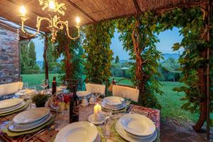 una mesa con platos y vasos en un jardín en VILLA IL TINAIO Romantic Secluded Farmhouse with Private Pool, en Valgiano