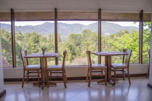 Habitación con 2 mesas, sillas y ventana grande. en VELINN Hotel Ninho do Falcão en Monte Verde