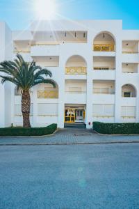 a building with a palm tree in front of it at Apartamento Sra da Rocha by Umbral in Porches