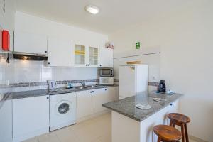a kitchen with white cabinets and a white refrigerator at Apartamento Sra da Rocha by Umbral in Porches