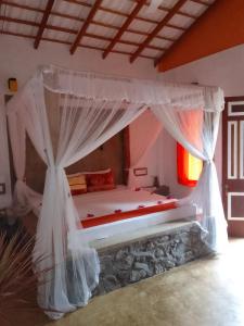 a bed with a canopy in a room at La Perla Bentota in Bentota